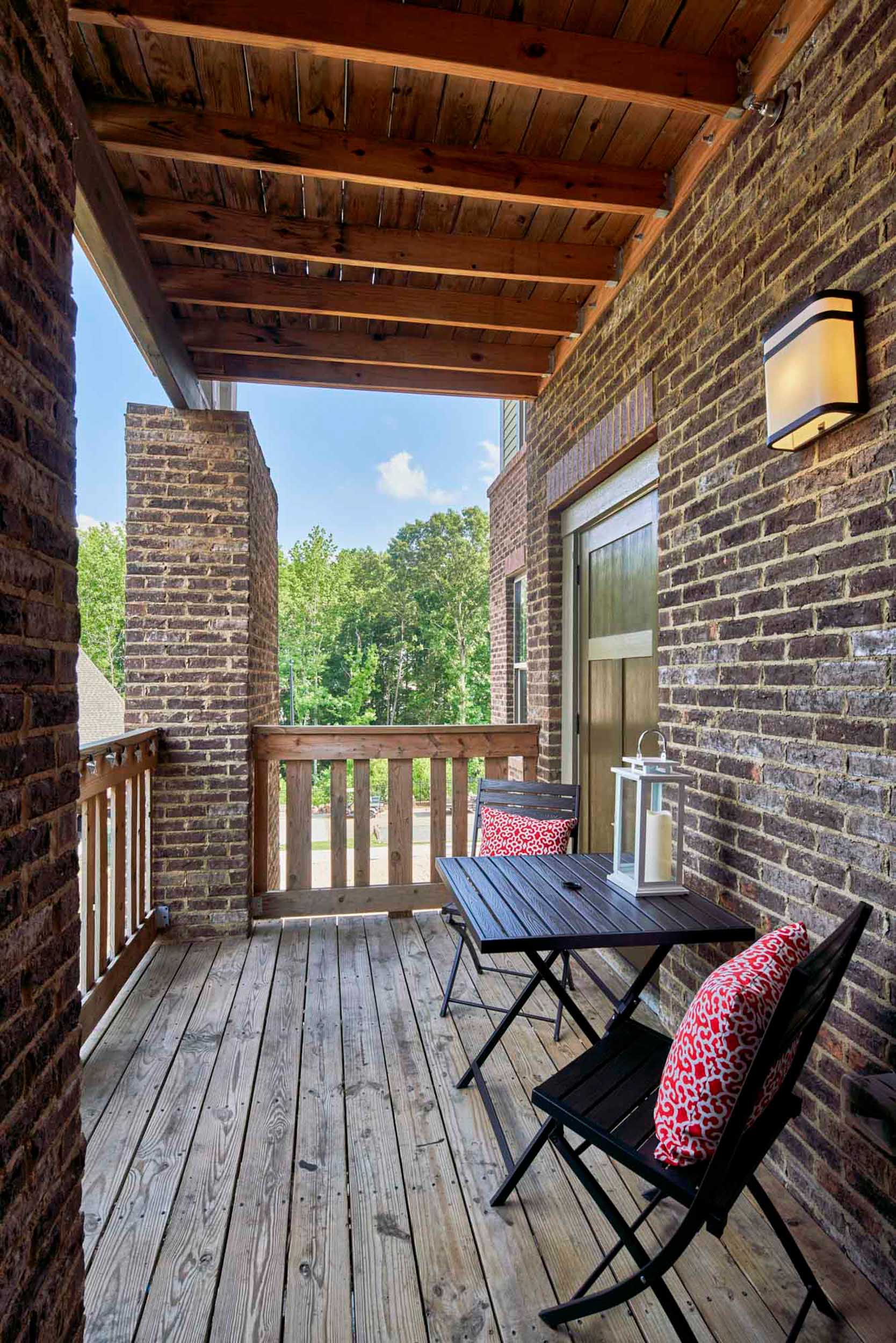 Porch with brick wall and wood balcony and overhang